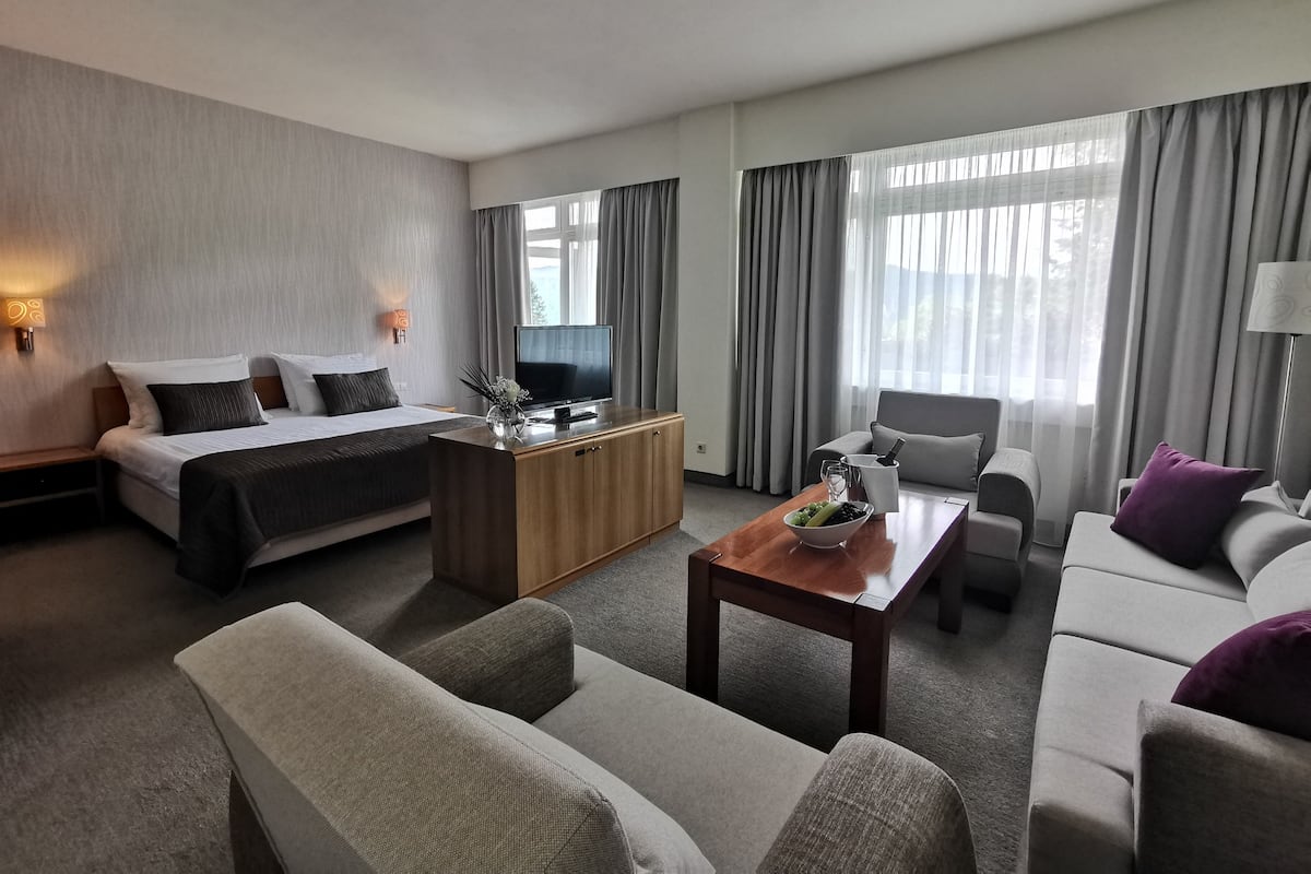 A hotel room with a bed, a TV, a desk, a sofa, and a coffee table.