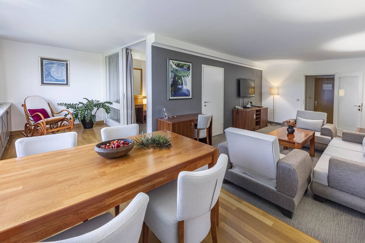 Un salon moderne avec une table à manger en bois, des canapés gris et un téléviseur.