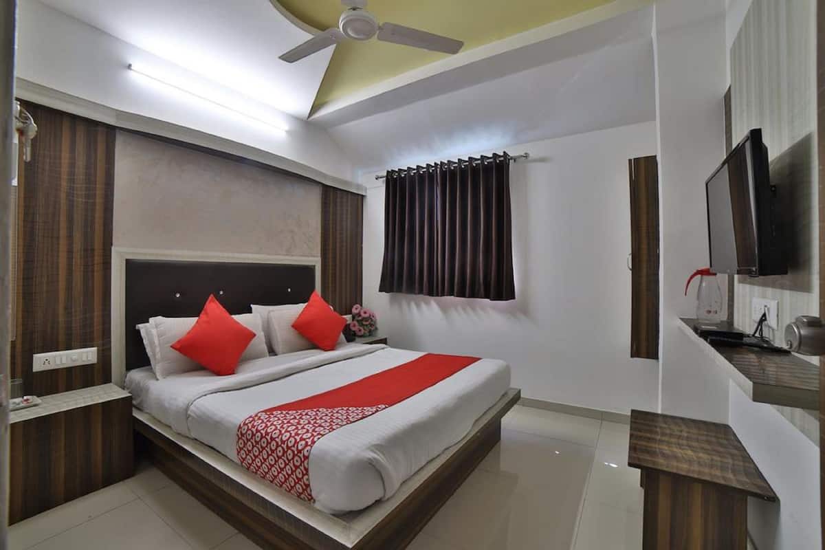 A hotel room with a bed, a TV, a desk, and a ceiling fan.