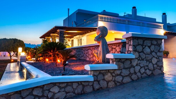 Una casa moderna con facciata in pietra, un balcone e illuminazione esterna.
