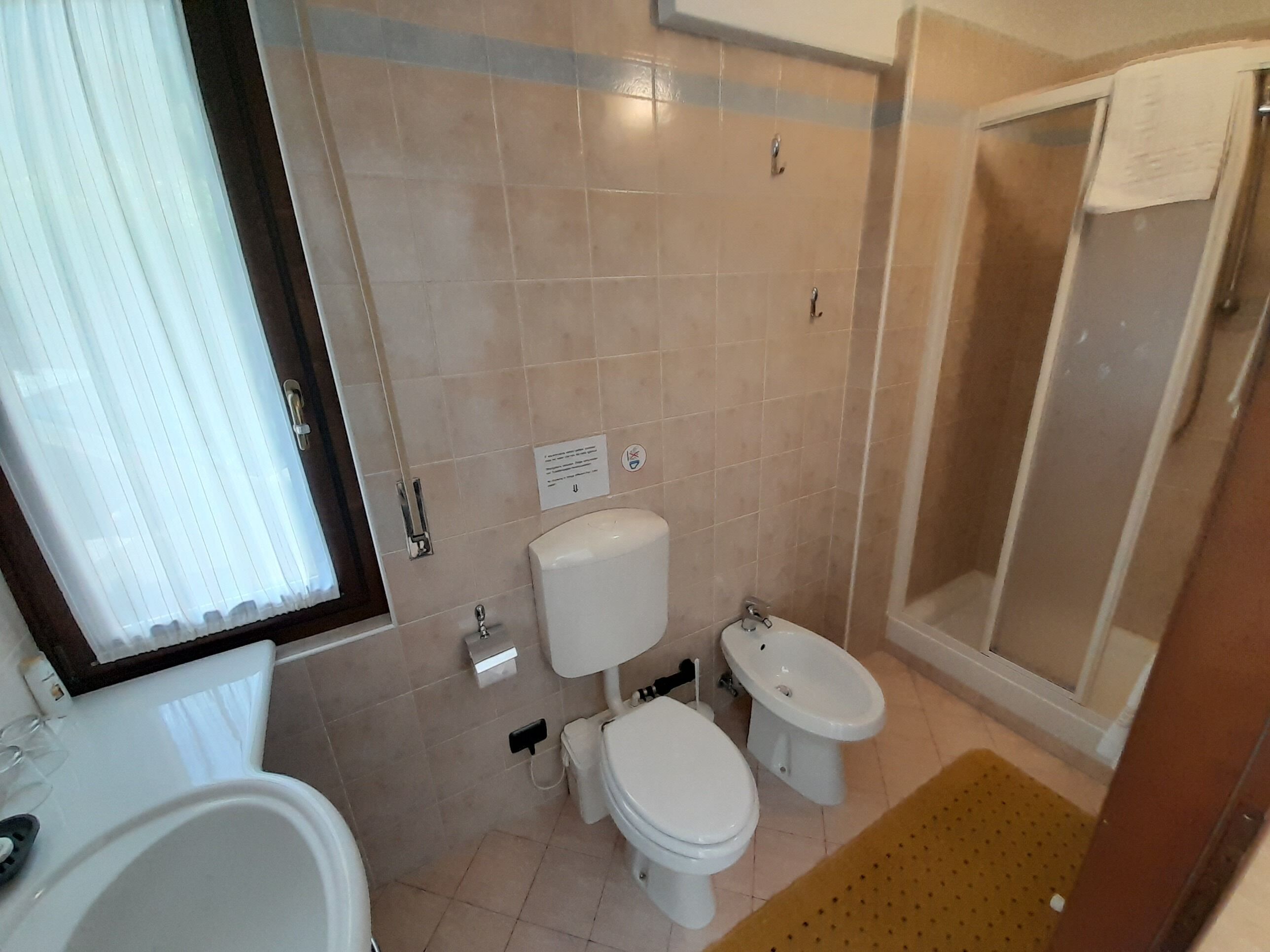 A bathroom with two toilets, a sink, and a shower.