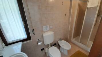 A bathroom with two toilets, a sink, and a shower.