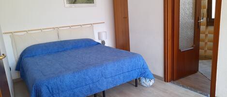A bedroom with a bed, wooden door, and a framed picture on the wall.