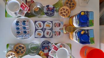 Ein Tisch, gedeckt mit Tellern, Besteck und verschiedenen Speisen, darunter verpackte Snacks und Getränke.