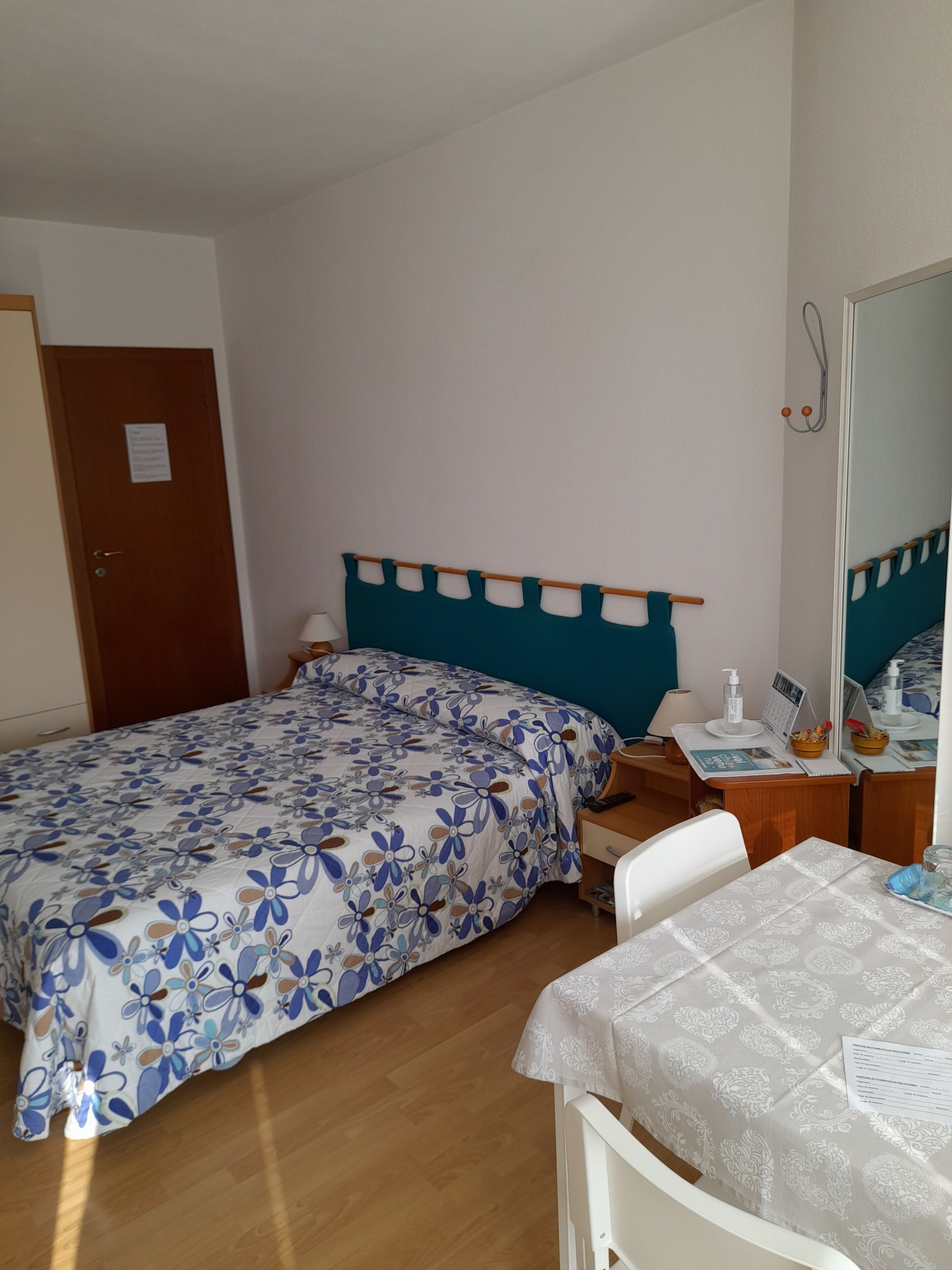 Ein Schlafzimmer mit einem Bett, Nachttischen, einem Schreibtisch und einem Spiegel.