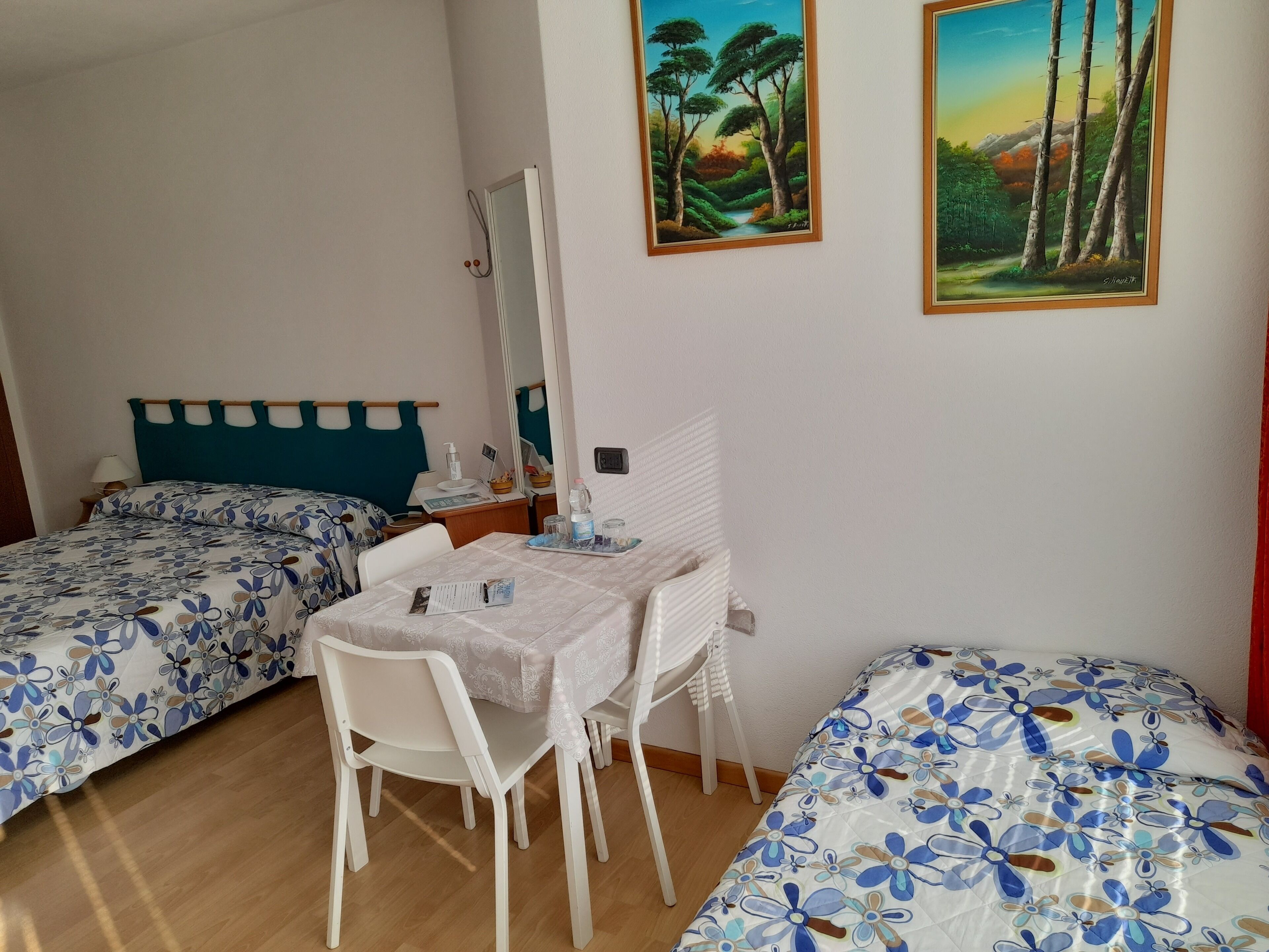 Un dormitorio con dos camas, un escritorio, una silla y dos cuadros en la pared.