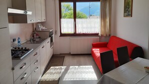 Una cocina compacta con ventana, un sofá rojo y una mesa de comedor.