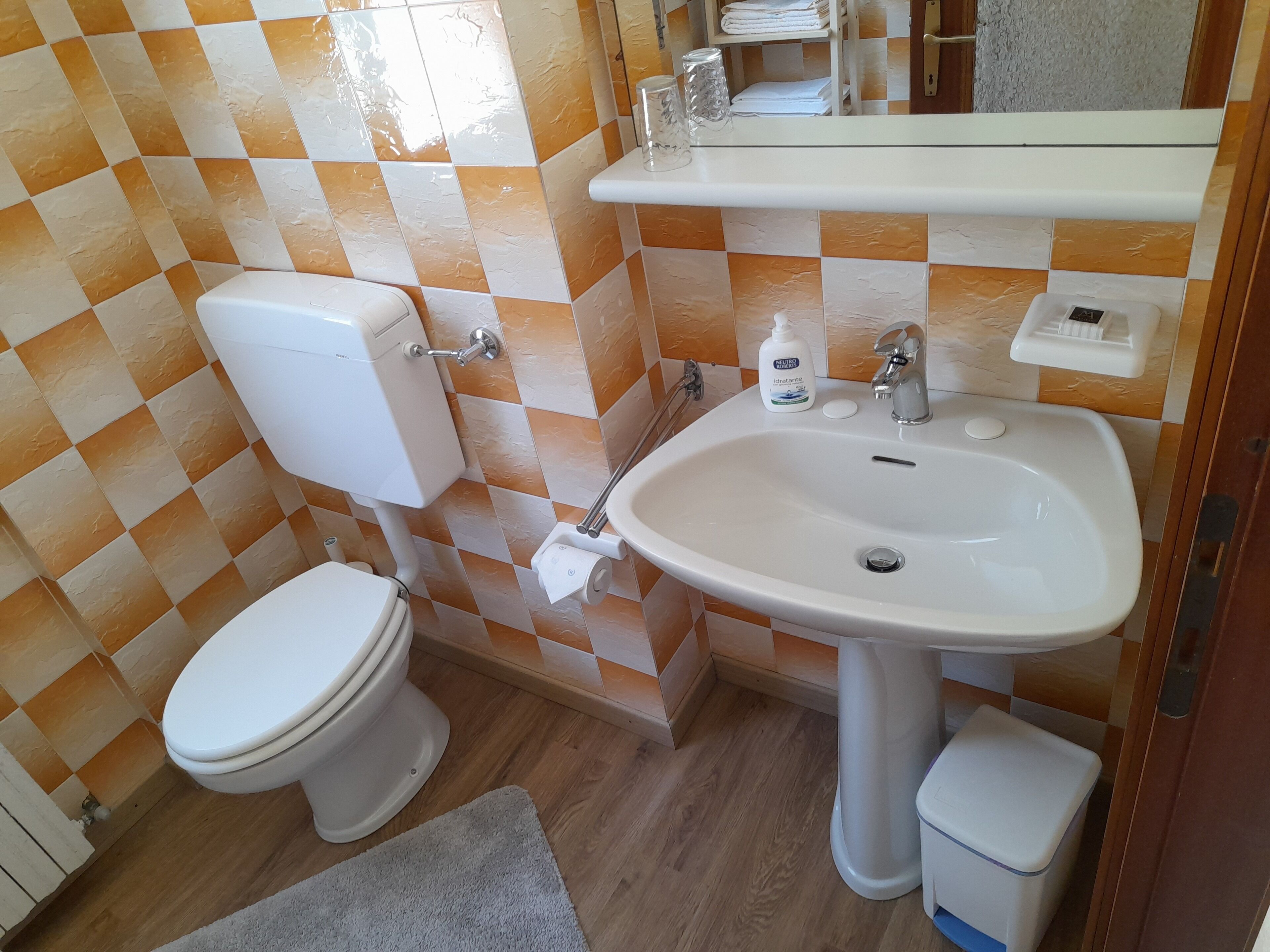 A bathroom with a toilet, sink, and a mirror.