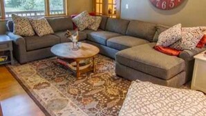 A living room with a sofa, a coffee table, and a large wall clock. - Beautiful home on Rifle River! Enjoy kayaking, outdoor fire, wildlife viewing (Prescott)