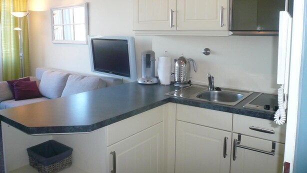 A compact kitchen with white cabinets, a built-in microwave, a sink, and a countertop. - App. Grimme 09 O, Germany (Sylt)