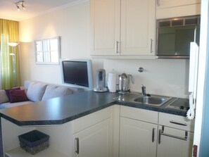 A compact kitchen with white cabinets, a built-in microwave, a sink, and a countertop. - App. Grimme 09 O, Germany (Sylt)