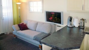 A compact living space with a sofa, a flat-screen TV, a coffee maker, and a kettle on a countertop. - App. Grimme 09 O, Germany (Sylt)