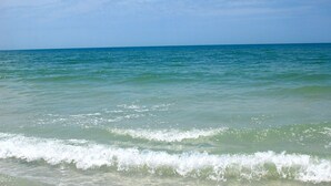 A beach with clear water and a clear sky.