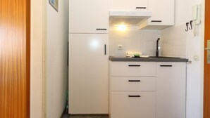 A compact kitchen with white cabinets, a built-in stove, and a sink.