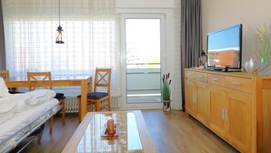 A hotel room with a bed, a dining table, a TV, and a view of the outside.