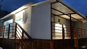 Um edifício com área externa coberta, escadaria e um logotipo na parede.