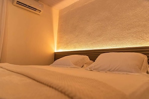 A hotel room with a bed, pillows, and an air conditioning unit on the wall. - Pousada Sunset Noronha (Fernando de Noronha)