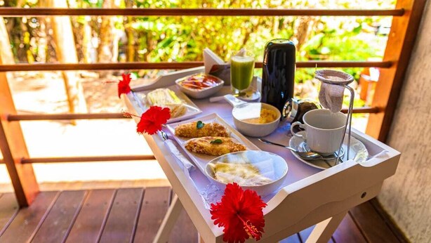 Bandeja de café da manhã numa varanda, com diferentes alimentos e uma bebida.