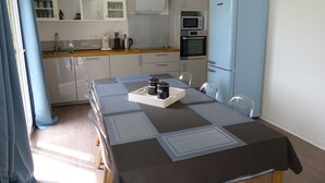 Una cocina moderna con armarios blancos, un refrigerador azul y una mesa de comedor con individuales y una bandeja.