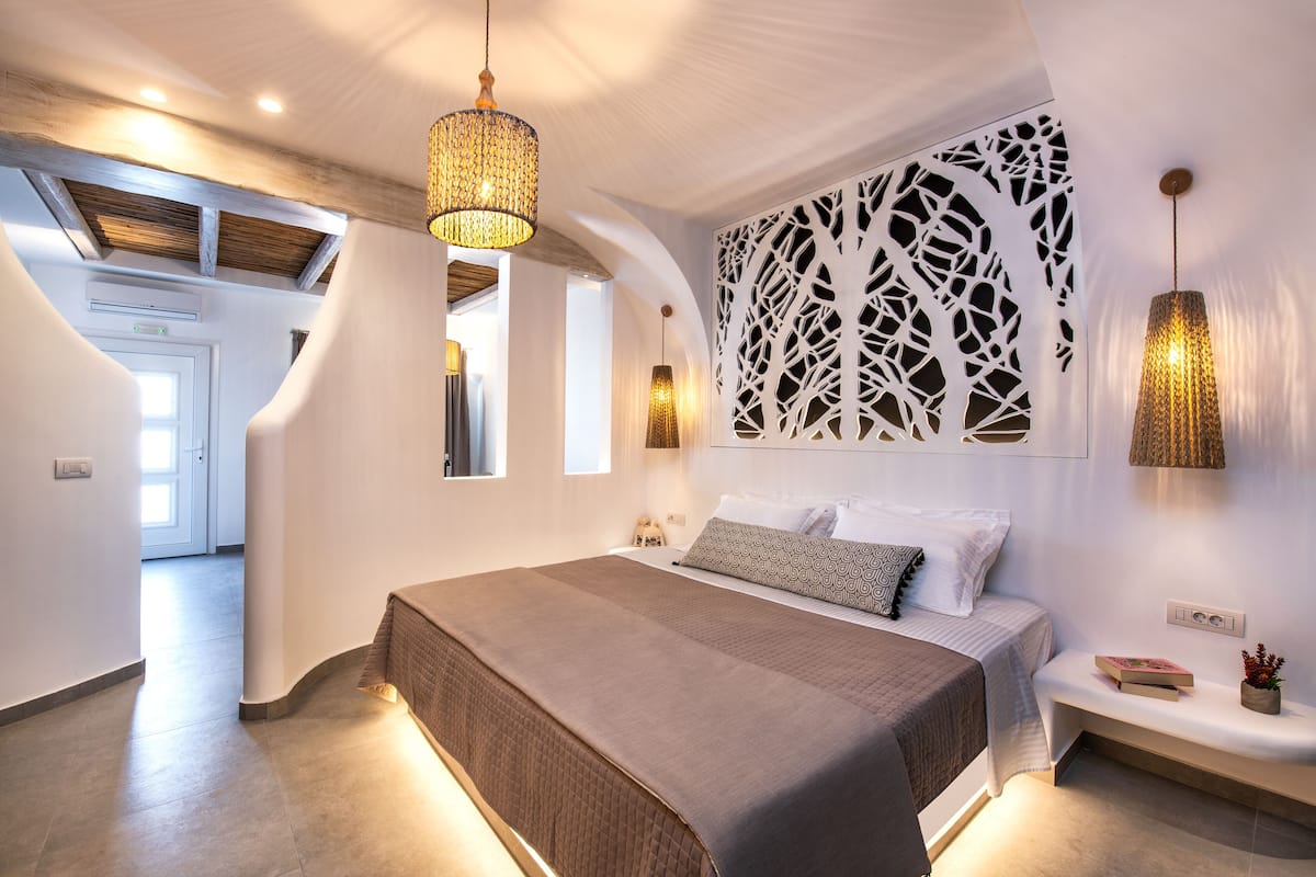 A modern bedroom with a large bed, a decorative wall panel, and a hanging light fixture.