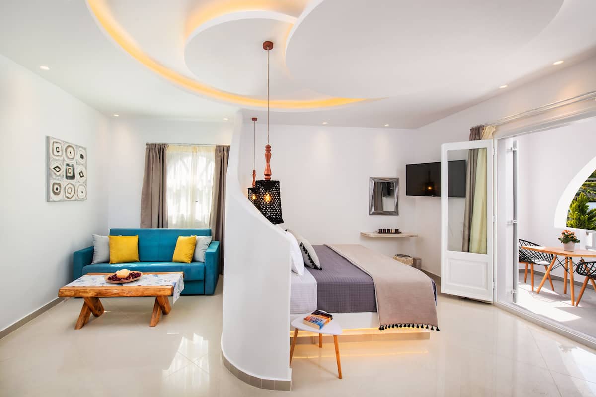 A modern living room with a blue sofa, a wooden coffee table, and a staircase leading to a bedroom.