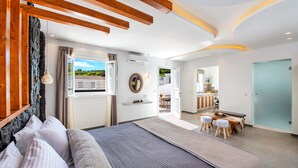 A modern bedroom with a large bed, a wooden ceiling, and a view of the outdoors. - Abasa Suites (Santorini)