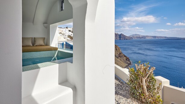 Ein Zimmer mit weißen Wänden und Blick auf das Meer und einen Pool.