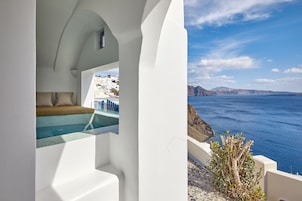 Una habitación con paredes blancas y vistas al mar y una piscina.
