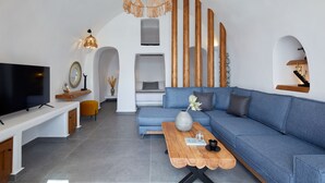 Ein modernes Wohnzimmer mit einem blauen Sofa, einem Holztisch und einem Fernseher auf einer weißen Kommode.