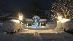 Schneebedeckte Landschaft mit einem beleuchteten Schneemann und einem Gebäude im Hintergrund.
