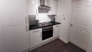 A modern kitchen with white cabinets, a black countertop, and stainless steel appliances. - Belvidere Apartments by Top House (Liverpool)