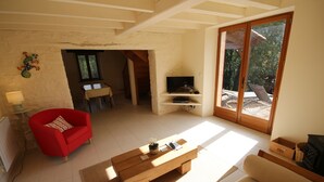 A living room with a red chair, a wooden coffee table, a sofa, a television, and a fireplace.