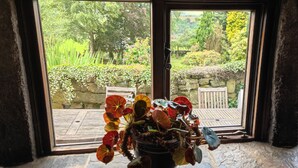 A view through a window with a stone wall and a wooden bench outside. - Greave Farm Todmorden Tranquil Cottage Retreat (Todmorden)
