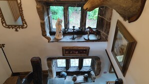 A rustic interior with a stone fireplace, a mounted horse statue, and a mirror on the wall. - Greave Farm Todmorden Tranquil Cottage Retreat (Todmorden)