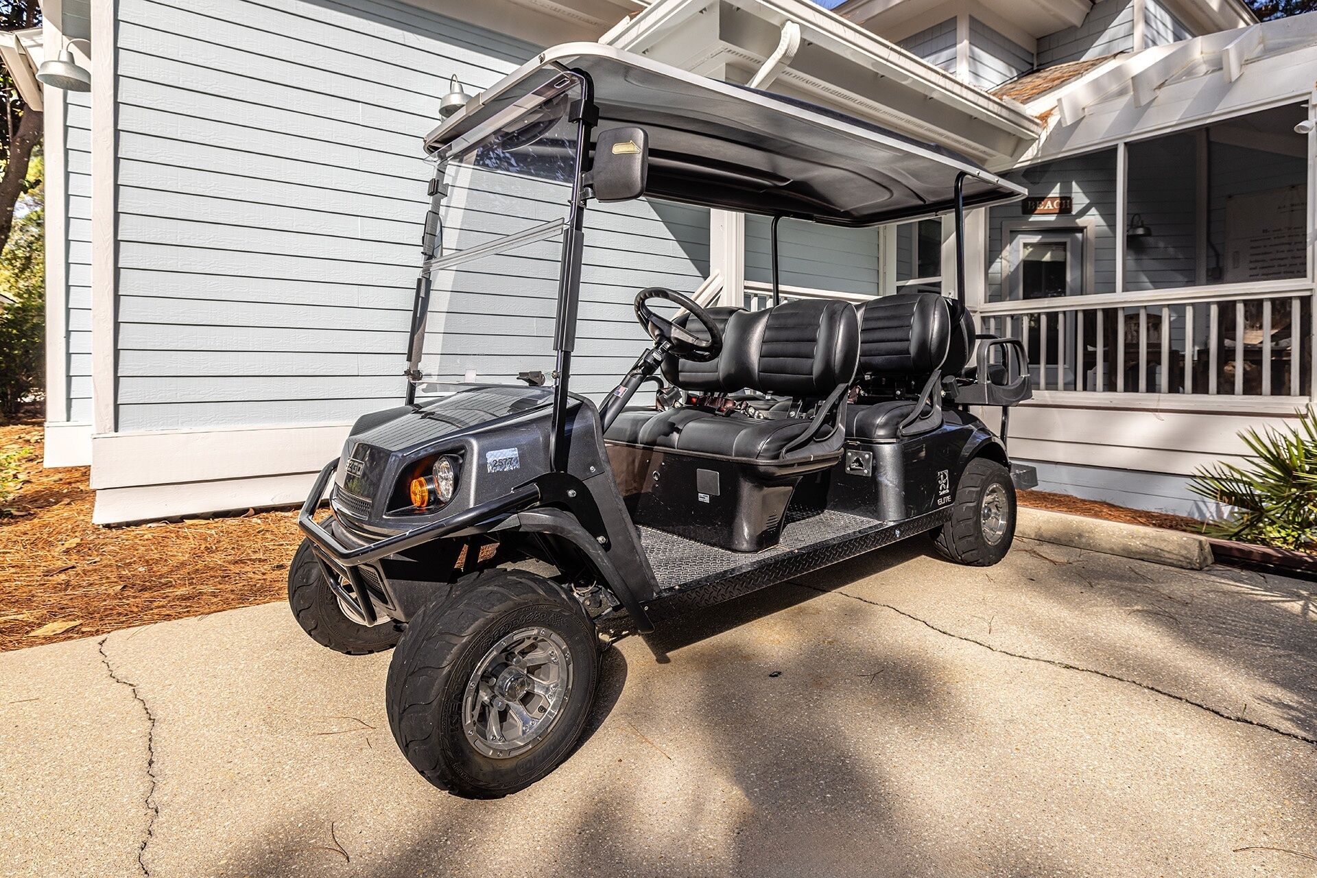 A golf cart parked in front of a house with a porch.