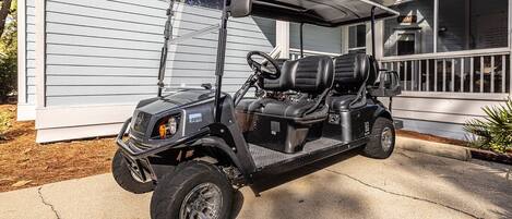 A golf cart parked in front of a house with a porch.