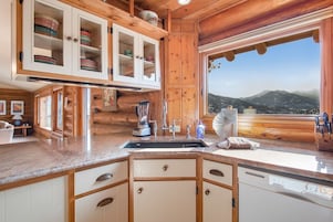 Cocina de cabaña de madera con un ventanal grande, armarios de madera y encimera de granito.