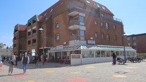 A multi-story building with a glass storefront labeled "VIA ROMA" and a sign for "PIZZERIA." - App. Hamelmann - with a small sea view (Sylt)