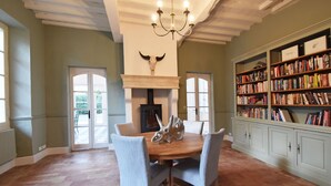Un comedor con una mesa y sillas de madera, una chimenea y una estantería llena de libros.