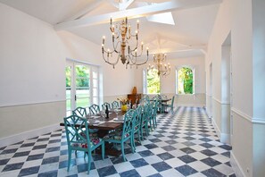 Un comedor con piso de cuadros, sillas color turquesa y candelabros.