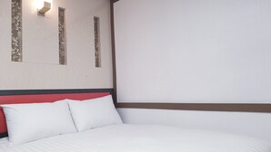 A neatly made bed with white bedding and a red headboard. There are two wall-mounted light fixtures with floral designs. - Hangeul Guest House (Seoul)