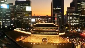 A traditional building with a large central archway, surrounded by modern high-rise buildings. - Hangeul Guest House (Seoul)