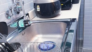 A stainless steel kitchen sink with a dish rack, a faucet, and a black appliance on the countertop. - Hangeul Guest House (Seoul)