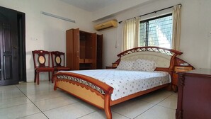 A bedroom with a wooden bed, a wardrobe, a chair, and a window with curtains. - Daon Guest House Dhaka (Dhaka)