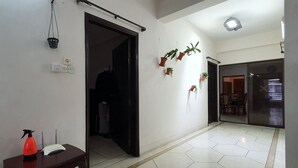 A hallway with a tiled floor, a door leading to a dark room, and several potted plants on the wall. - Daon Guest House Dhaka (Dhaka)