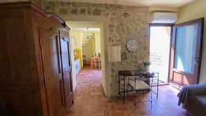 A kitchen with a stone wall, a wooden cabinet, a dining area with a table and chairs, and a small table with a plant. - The casina of the NOT time downstairs (MONTEBUONO DI SORANO)