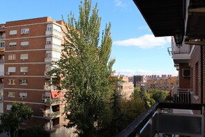A multi-story building with balconies and a large tree in front.