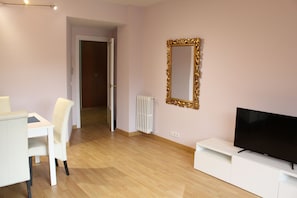 A modern living room with a flat-screen TV, a white entertainment unit, and a large ornate mirror on the wall. - Amplio apartamento, Madrid Centro. WIFI (Madrid)