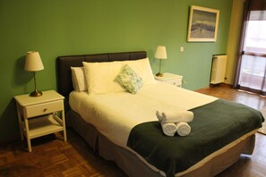 A neatly made bed with a green blanket, two bedside lamps, and a small nightstand with a lamp. - Amplio apartamento, Madrid Centro. WIFI (Madrid)