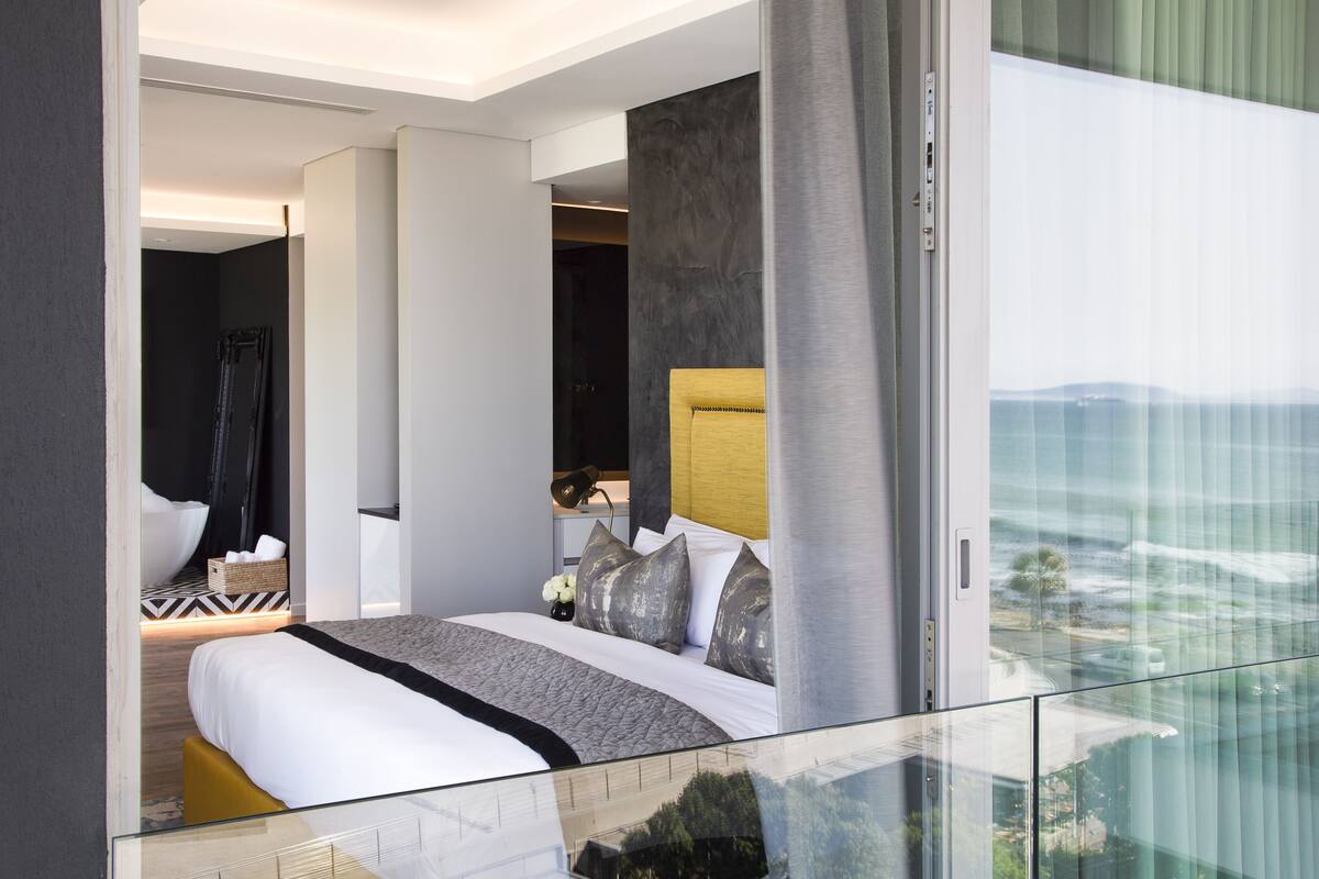 Une chambre d’hôtel moderne avec un grand lit, une vue par la fenêtre et un balcon.